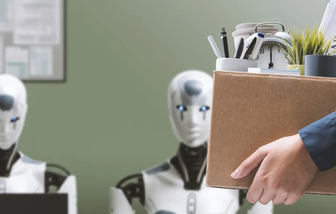 Person carrying cardboard box full of belongings past a line of robots
