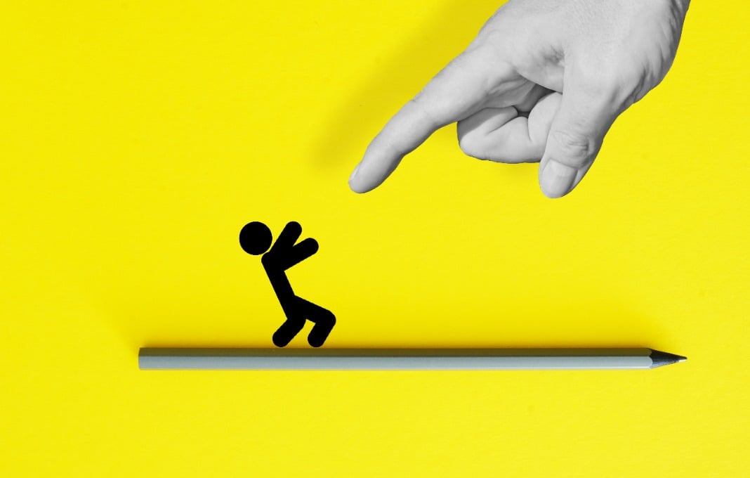 Giant finger pointing at stick figure illustration on yellow background