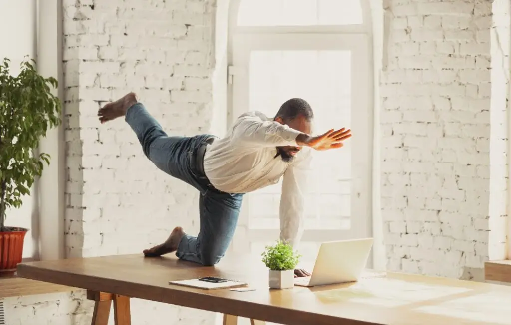 man doing yoga at home while being quarantine and freelance online working.