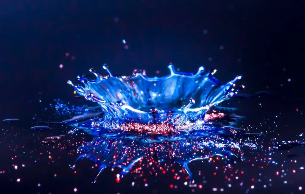 Drops of water colliding with powdered dye to create a multi coloured abstract droplet collision