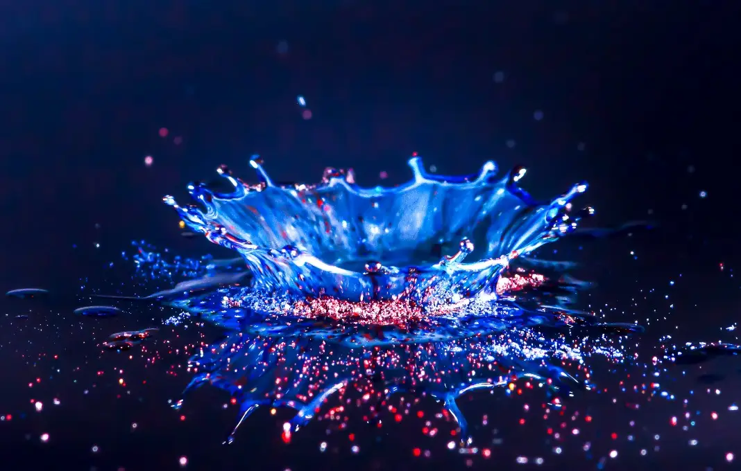 Drops of water colliding with powdered dye to create a multi coloured abstract droplet collision