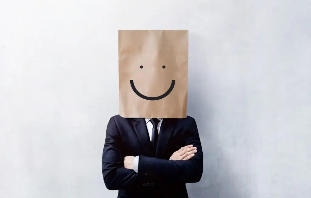 Businessman with paperbag with smiley face drawn on over head