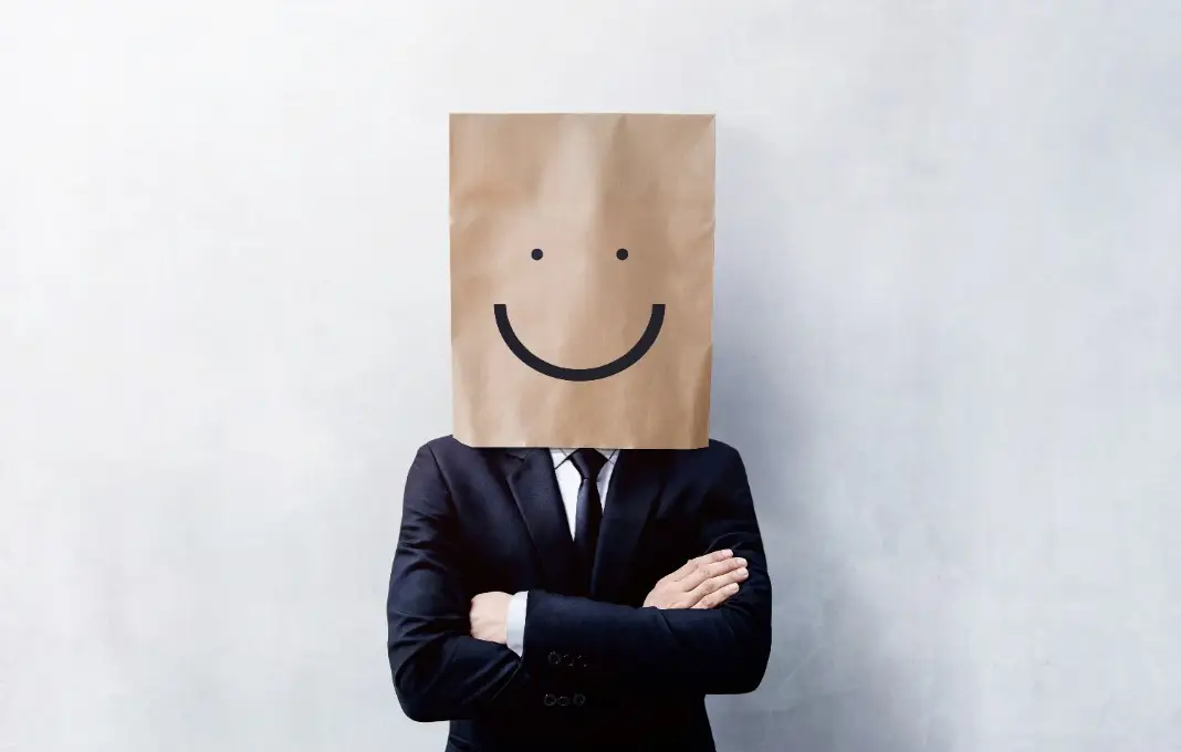 Businessman with paperbag with smiley face drawn on over head